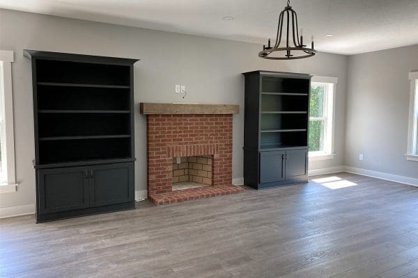Open family room with painted brick fireplace, built-in shelving, luxury vinyl plank flooring, and modern lighting.