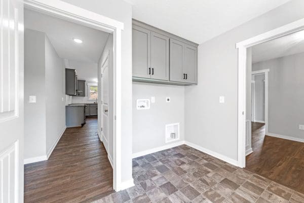 Laundry room with upper storage cabinets, washer and dryer hookups, and tile flooring.