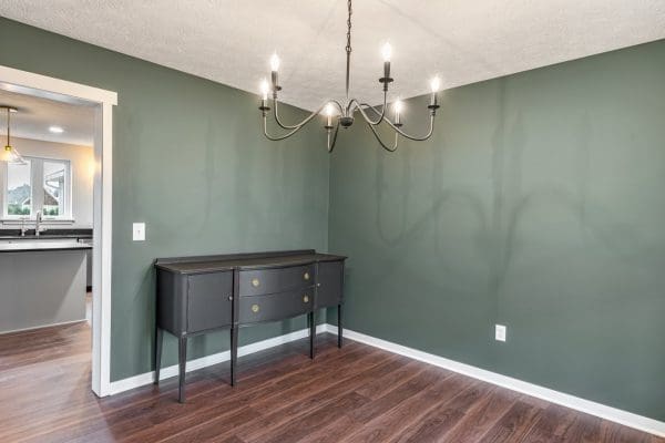 Dining area with green walls and standard chandelier.