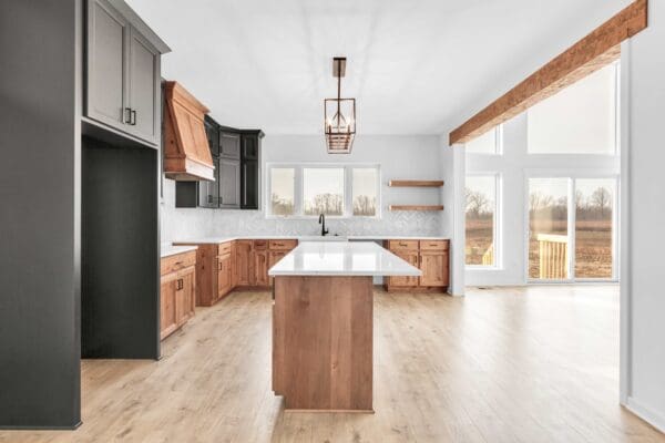Bright open-concept kitchen featuring a wood island, black and natural wood cabinets, floating shelves, and large windows.