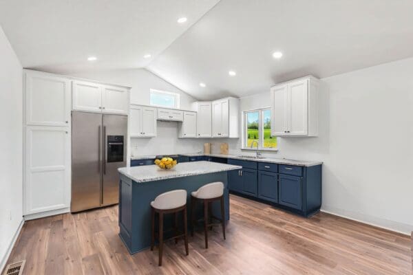 Kitchen of the Pendleton with white upper cabinets and blue lower cabinets and a blue island..