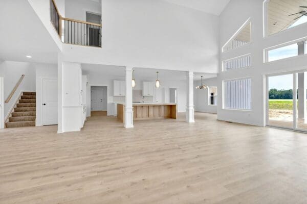 Family room with a vaulted ceiling, large windows, and an open view into the kitchen.