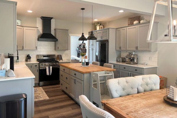 Open-concept kitchen with a large wood-tone island, white cabinetry, quartz countertops, and stainless steel appliances.