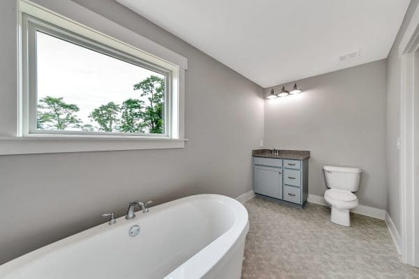 Primary bathroom with a freestanding soaking tub, gray walls, and large picture window.