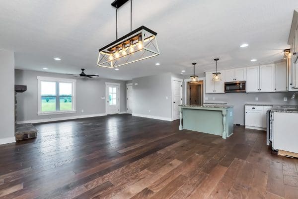 Open-concept family room with hardwood flooring, modern chandelier, and views into the kitchen.