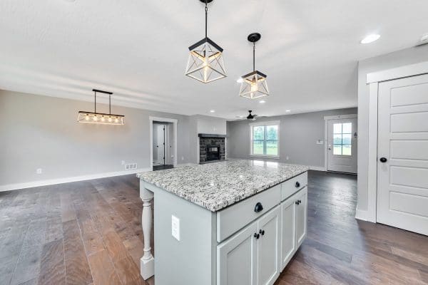 Bright kitchen with a large light green center island, pendant lighting, and quartz countertops.