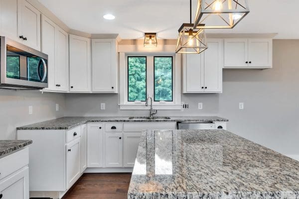 White kitchen with quartz countertops, subway tile backsplash, and large window over the sink.