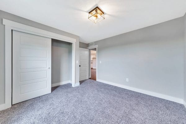 Bright bedroom with carpet flooring, neutral walls, and spacious closet.