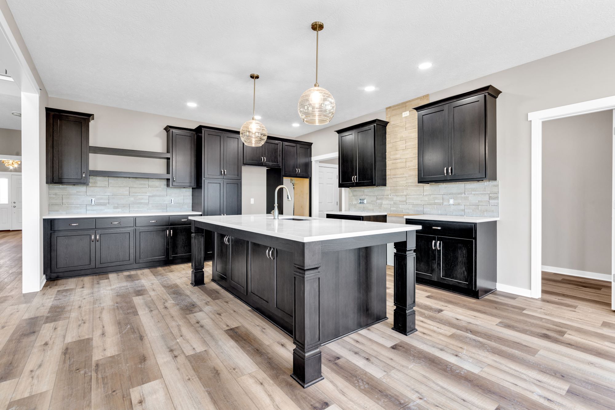 Kitchen of a modified two story custom home called the Crestline featured dark stained custom cabinets and open shelving.