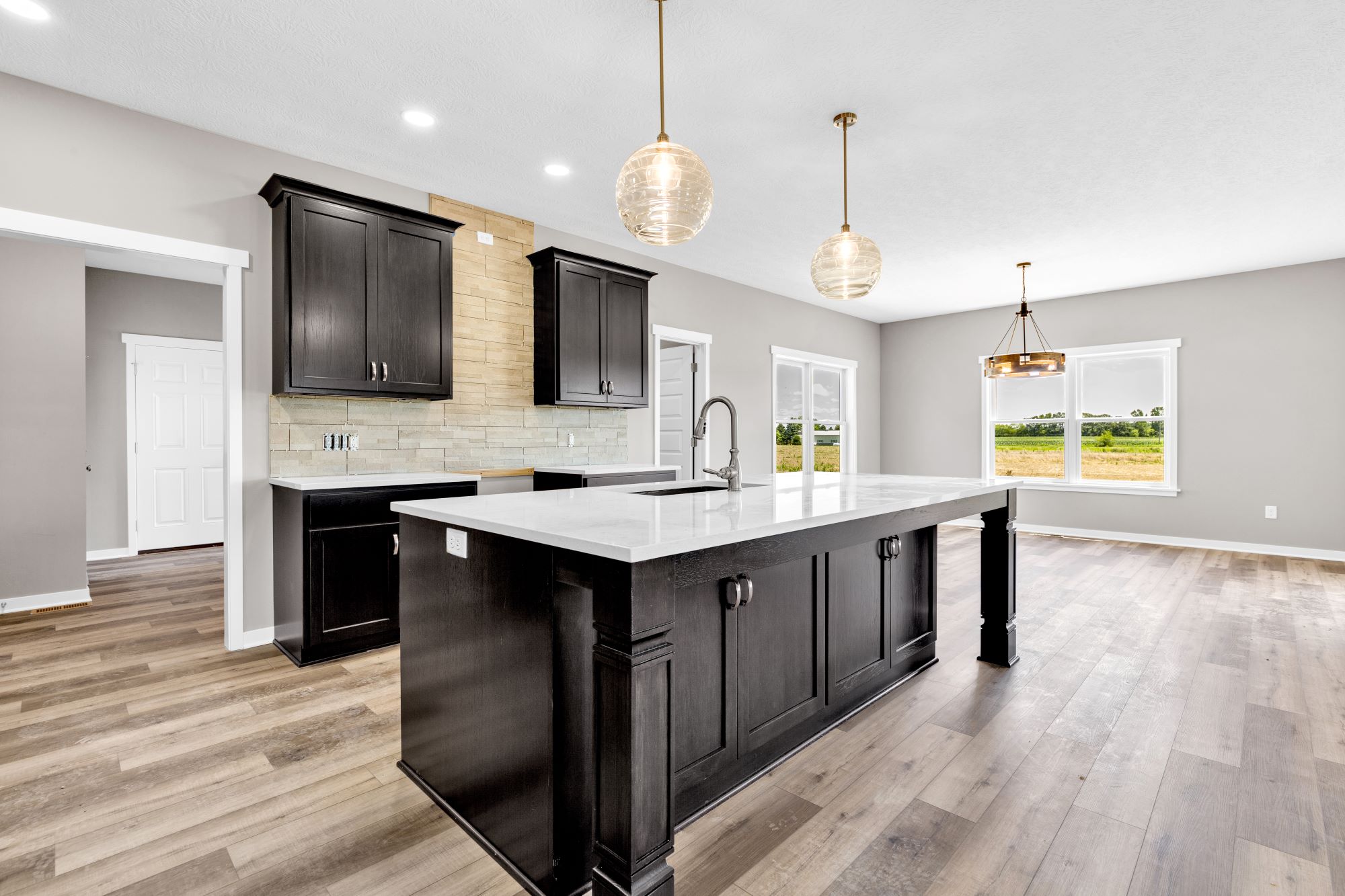 Kitchen open to the dining area of a modified two story custom home called the Crestline - kitchen features custom cabinets and dining room has lots of windows.