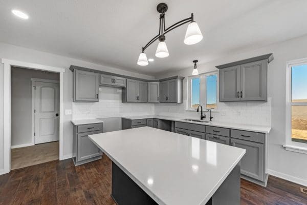 Kitchen with medium gray cabinets, iron ore island and quartz counters.