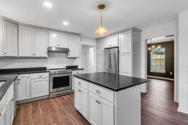 The Adams with white kitchen and black countertops and stainless appliances.