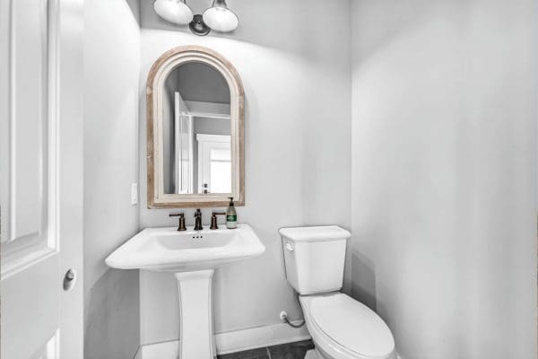White Powder Room with half round mirror and black fixtures.