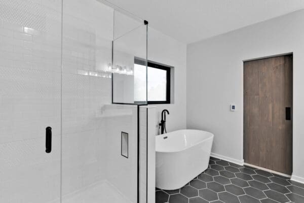 Primary bathroom with a frameless glass walk-in shower, freestanding soaking tub, and modern black fixtures.