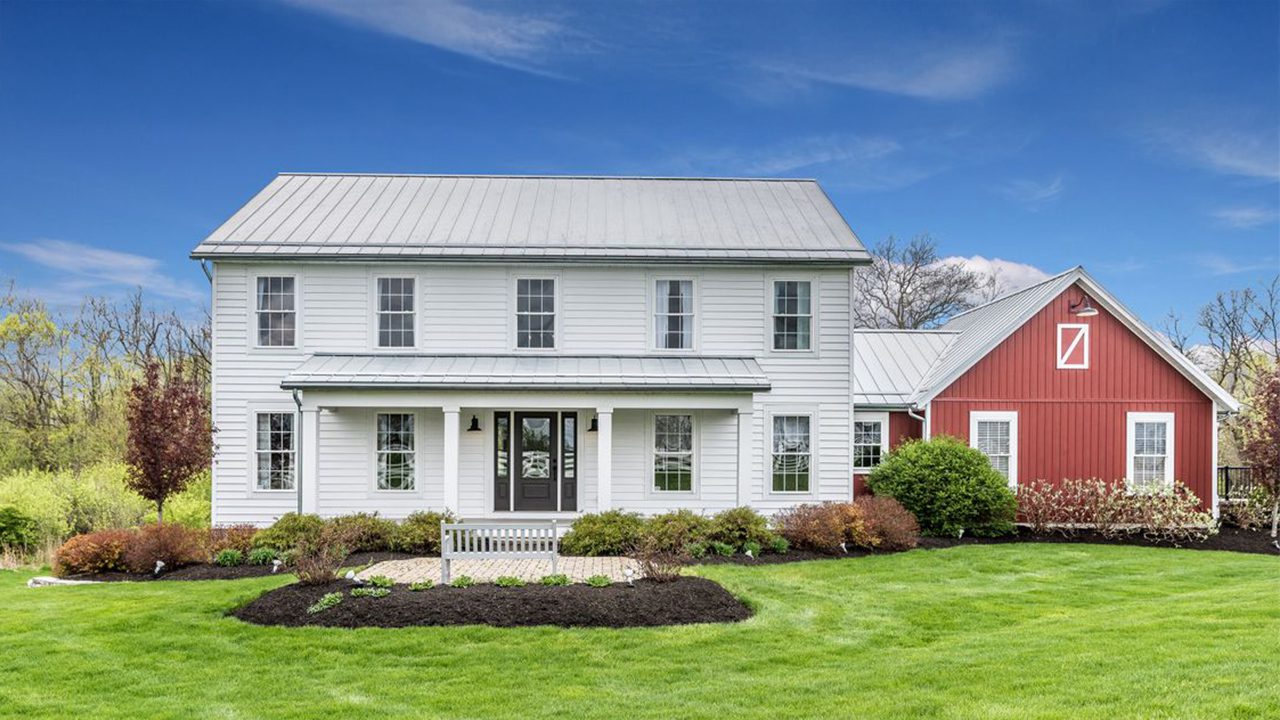 Video walk through photograph of the Madison II farmhouse with white and red siding.