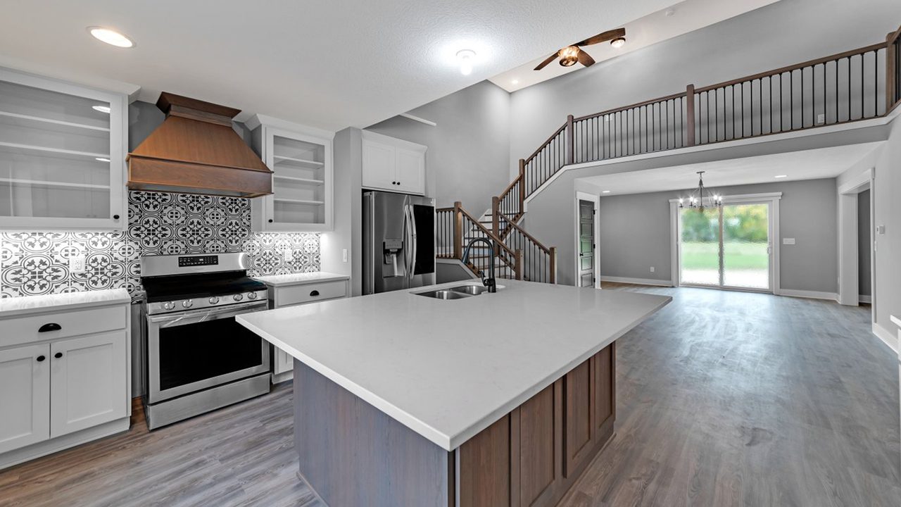 Custom kitchen with custom cabinets, stained range hood and filagree back splash.