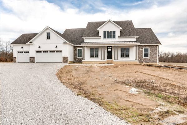 Front elevation of a custom two-story farmhouse with covered front porch and attached garage.