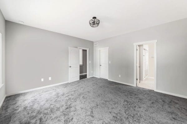 Spacious primary bedroom with plush carpeting, recessed lighting, and abundant natural light.