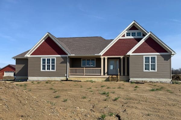 The Dover floor plan with red in gables and tan siding.