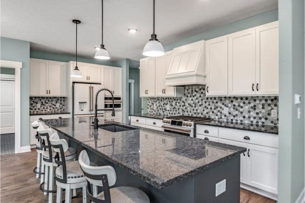 Custom kitchen with dark countertops and black and white backsplash.