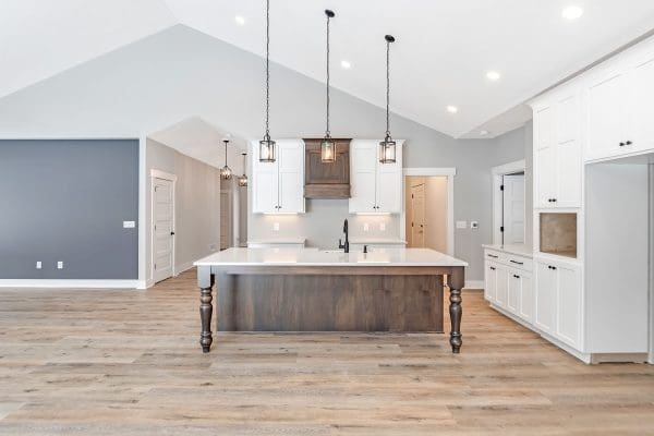 Custom home with stained island and hood with white perimeter cabinets.