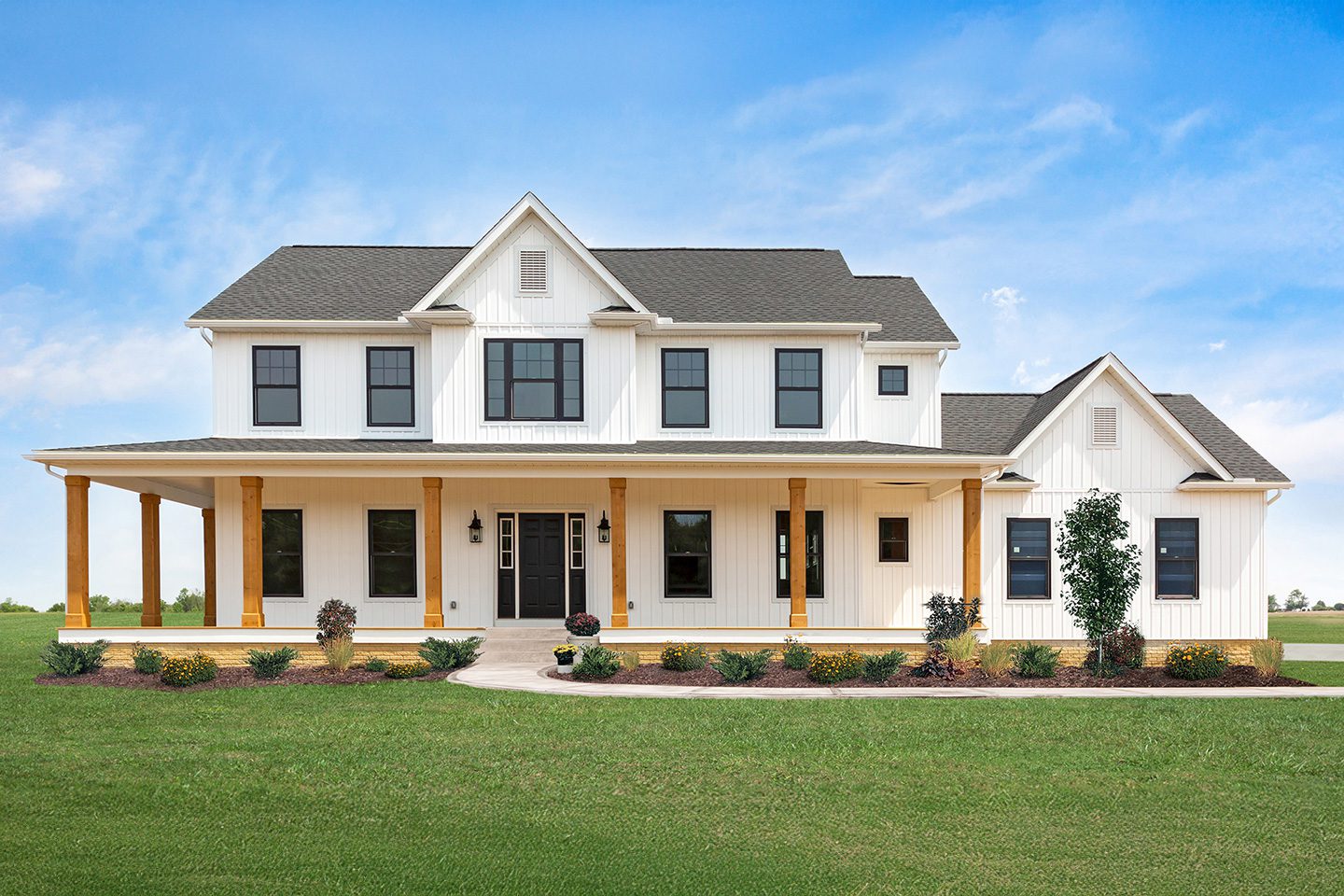 Custom two-story white farmhouse-style home with black shutters, covered front porch, and attached garage built by American Heritage Homes.