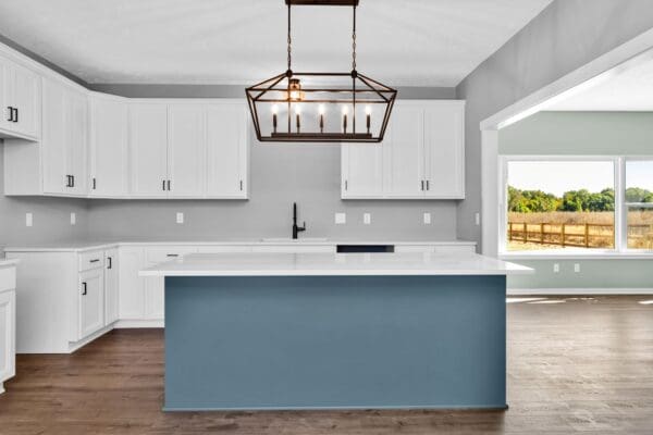 Modern kitchen featuring a blue center island, white shaker cabinets, quartz countertops, black hardware, and a large geometric pendant light over the island.
