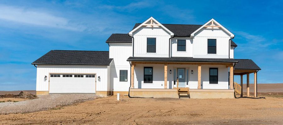 Modified Adams farmhouse with white siding, black roof and stained gable brackets main blog header image.