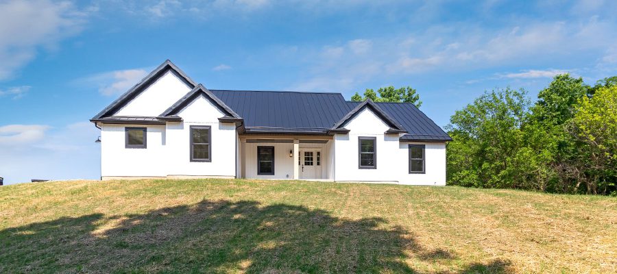 An exterior photo of the Clark with black metal roof, white board and batten siding and black windows.