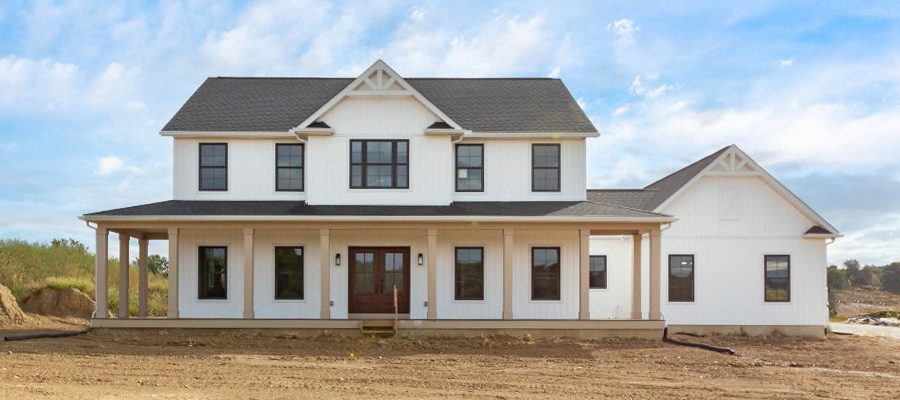Two story custom Madison II with full wrap around porch, white siding and double entry doors.