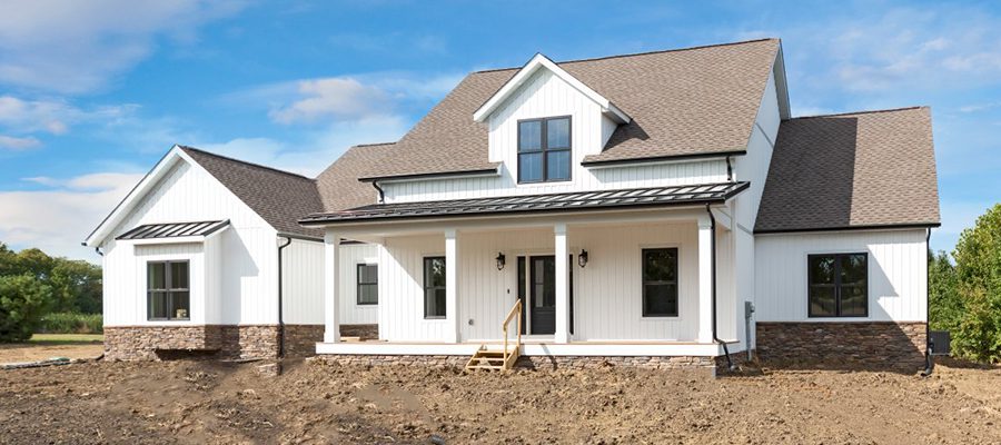 Charles Pointe with gray shingles, metal roof above porch, black windows and white board and batten siding.