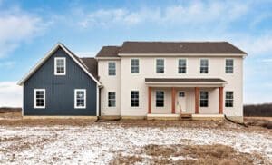 Exterior of a two story custom home with antique white horizontal siding on house and sea slate board and batten on garage.