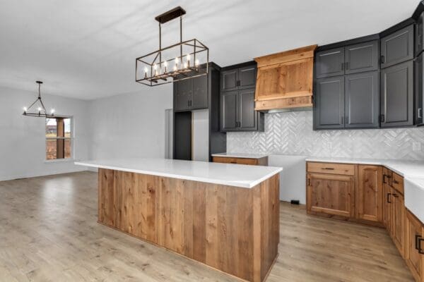 Modern kitchen with island, black cabinetry, natural wood accents, and geometric pendant lighting.