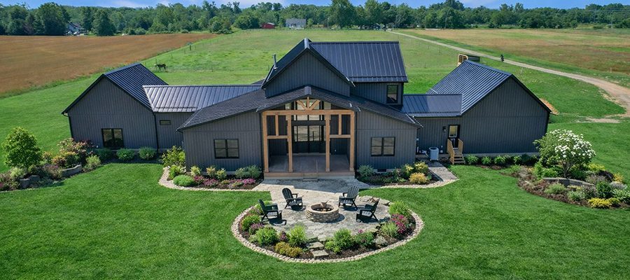 Custom modern farmhouse in Central Ohio with landscaped backyard, fire pit patio, and green lawn on rural land.