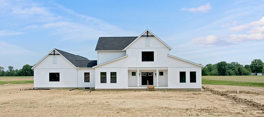 Exterior of a two story farmhouse home with a private living space in the rear.