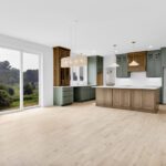 Open dining room and kitchen with white oak flooring and green and stained wood cabinetry
